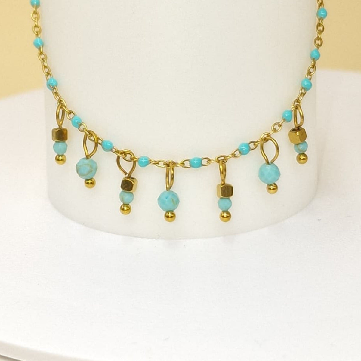 bracelet en acier inoxydable doré, orné de perles bleues turquoises et de pampilles. Un bijou délicat à porter seul ou avec d’autres bracelets