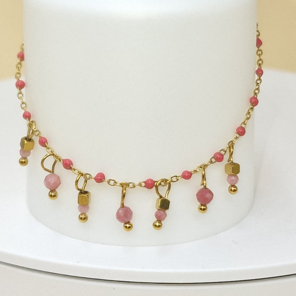 bracelet en acier inoxydable doré, orné de perles roses et de pampilles. Un bijou délicat à porter seul ou avec d’autres bracelets