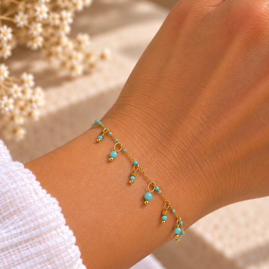 bracelet en acier inoxydable doré, orné de perles bleues turquoises et de pampilles. Un bijou délicat à porter seul ou avec d’autres bracelets